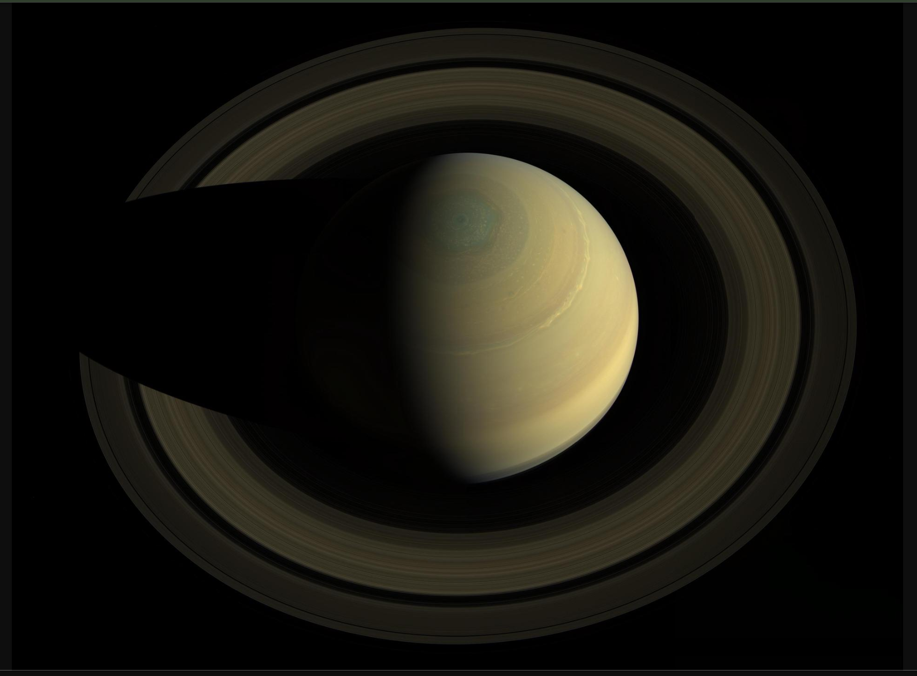 Cassini view of Saturn from above the north pole, showing the polar hexagon and ring shadows.