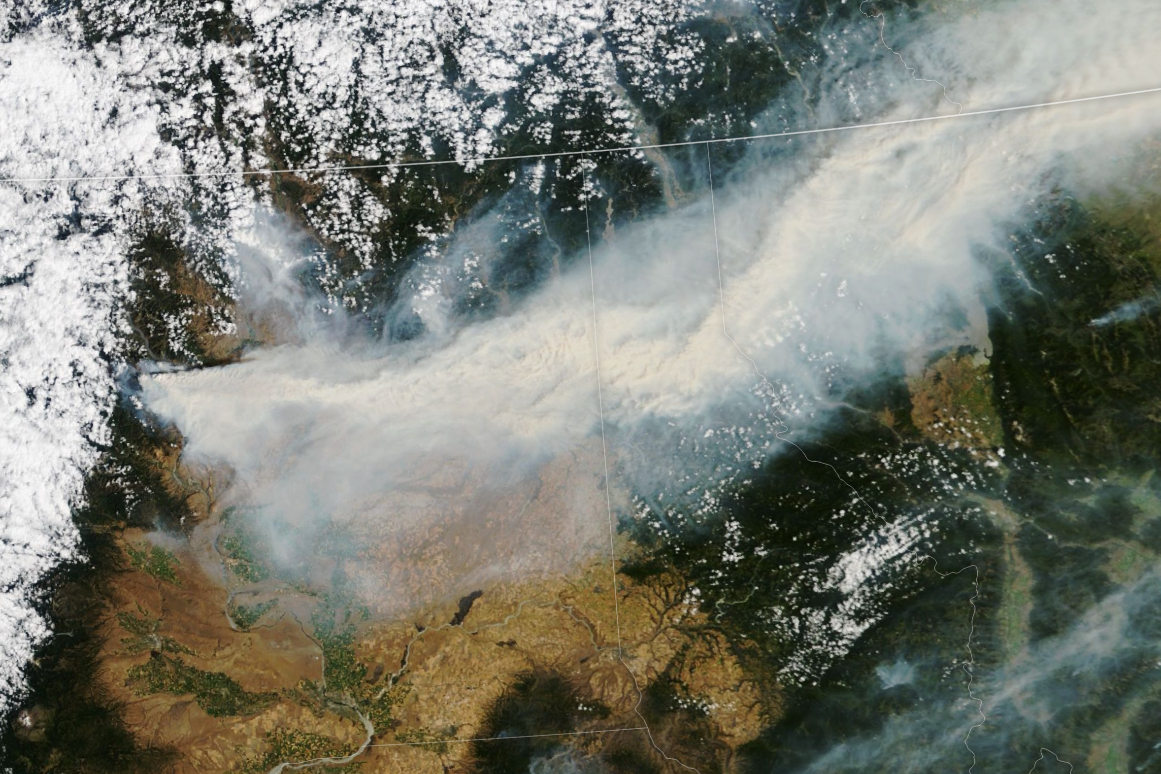 NASA MODIS/Terra satellite image of a wide plume of wildfire smoke streaming east across Washington, Idaho, Montana, and Canada on August 2, 2026.